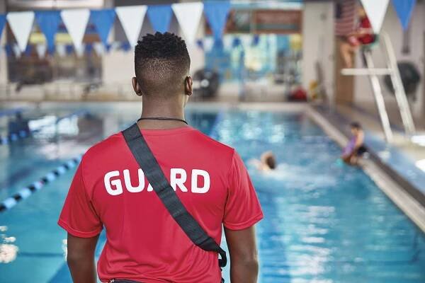 Lifeguard overlooking pool while children play