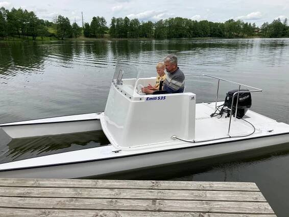 EMILI 535 catamaran on the lake with an adult steering it and a child next to him