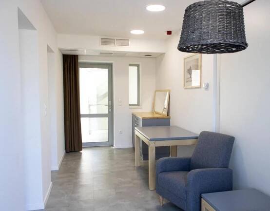 a living room with a desk and a chair and a lamp at Tornácos Hotel - Hegykő in Hegykő
