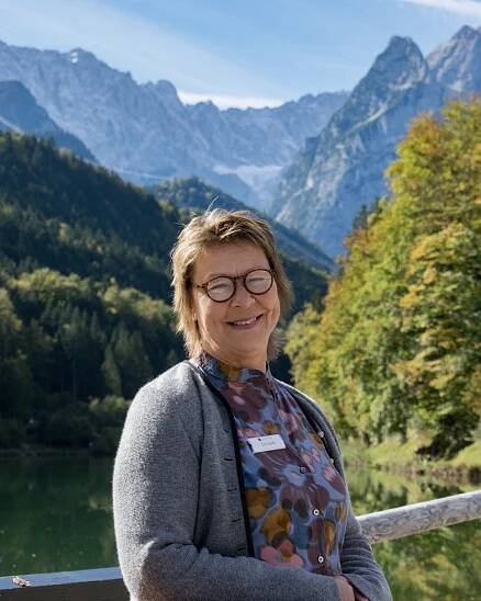Portraitfoto von der Mitarbeiterverwalterin Ute Stark. Im Hintergrund sind die Berge und der Riessersee zu sehen.