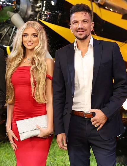 Princess Andre, in a red dress, and Peter Andre, in a blue suit, at a film premiere in 2025.