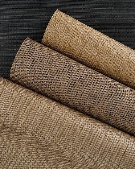 Multiple rolls of intricately woven natural wallpaper.