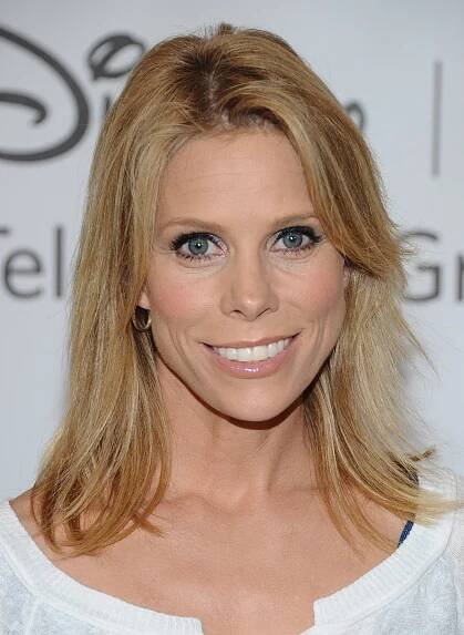a woman with blonde hair and blue eyes smiles at the camera while wearing a white top