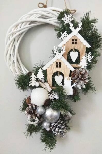 a wreath with a birdhouse and snowflakes hanging from it's side