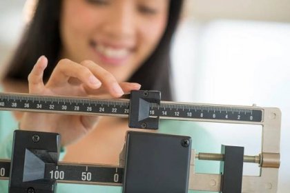 Bránice žena s úsměvem při nastavování váha měřítko — Stock fotografie