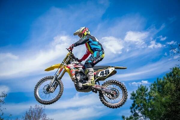 Photograph of Kevin Cozaad jumping his dirt bike with blue sky in the background at a private track in Gainesville, Fl.