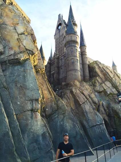 Man standing outside of Hogwarts Castle at the Wizarding World of Harry Potter in Orlando