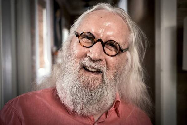 a man with a beard wearing glasses and a pink shirt