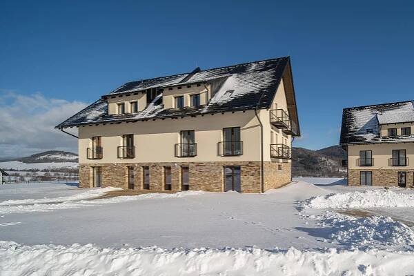 a building with snow on the ground in front of it at Apartmán U Suchého buku - Buková Hora in Červená Voda