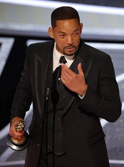 Will Smith on stage, crying and holding an Oscar