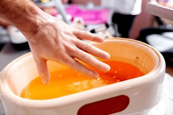 person putting hand in paraffin wax