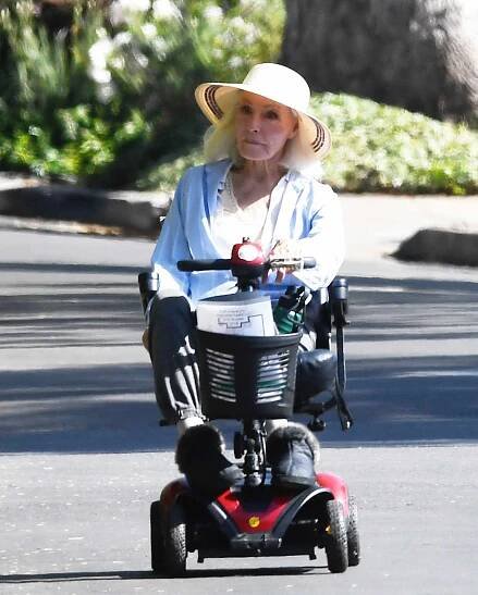 Person in a hat riding a motorized scooter outdoors
