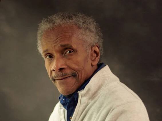 A man with gray hair and a white sweater