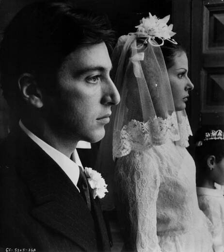 a man and woman standing next to each other in front of a doll wearing a wedding dress