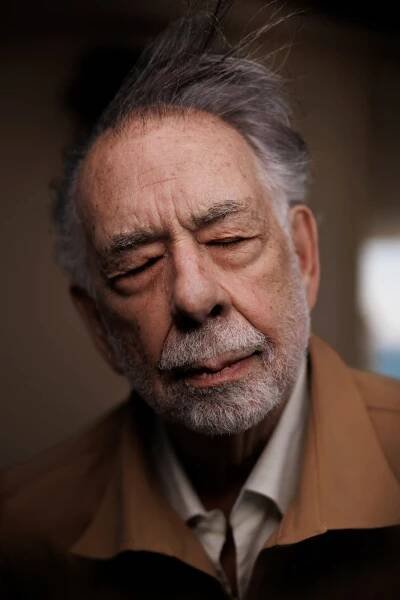 In a close-up portrait, Francis Ford Coppola’s thinning gray hair is being blown upward as he closes his eyes.