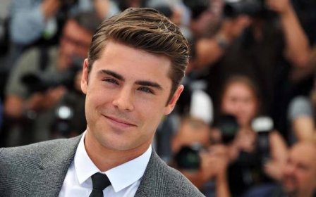 Zac Efron grinning cheekily in a close-up Wallpaper