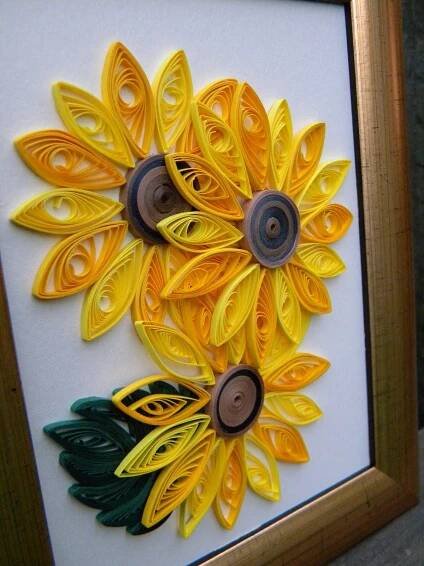 an art piece made out of yellow and green paper with buttons attached to it, sitting in a wooden frame