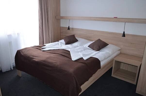 a large bed with white sheets and pillows at Hotel ČESKÁ FARMA in Dolni Dvur