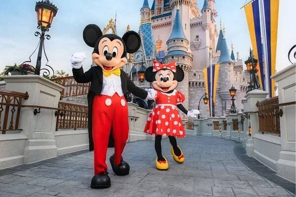 Mickey and Minnie holding hands in front of Cinderella Castle