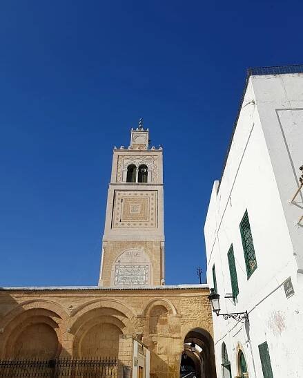 View of some of the buildings in the Tunis medina, including the golden stone of a mosque minaret and gleaming white walls - how to spent two days of a city break in Tunis