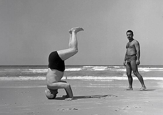 David Ben Gurion, izraelský premiér, se staví na hlavu na pláži v Herzliji v...