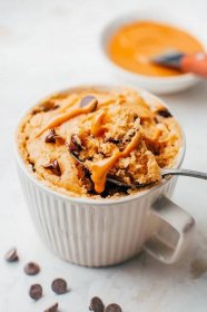 Peanut butter mug cake with chocolate chips, drizzled with peanut butter.