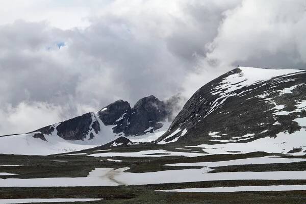 Clouds float through the snowy mountains of Dovrefjell. With Snøhetta on the right side of the photograph - Norway