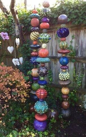 a garden filled with lots of different colored vases and flowers next to a wooden fence