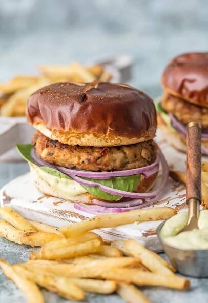 Las hamburguesas de pollo con queso feta y tomate secado al sol son una de mis recetas saludables favoritas para arrojar a la parrilla. ¡Estoy viviendo para esta RECETA DE HAMBURGUESA Y POLLO DE TOMATE SECO AL SOL! Haga estas hamburguesas de pollo molido asando en la estufa o al aire libre una vez que el clima coopere para obtener el mejor alimento para su comodidad. La combinación de sabores mediterráneos en estos sándwiches está fuera de este mundo, especialmente cuando se cubre con una mayonesa de pesto fácil.