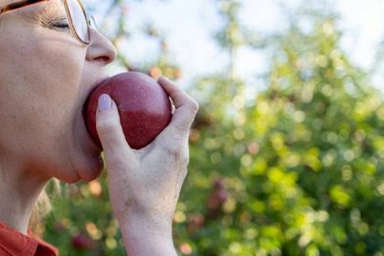 a woman eating an apple with her eyes closed