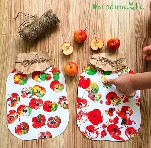 two apples are sitting on the table with paper and twine around them, while someone is holding an apple in their hand