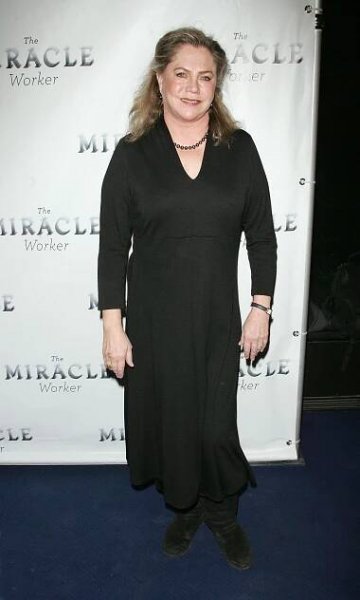 At the Broadway opening of "The Miracle Worker" in New York City, Kathleen Turner is seen wearing a simple, elegant long black dress paired with black boots, accessorized with a delicate necklace, presenting a refined and understated look for the event.