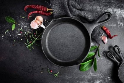 Cast iron pan and spices on black metal culinary background — Stock obrázek