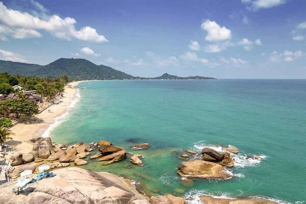 Blick auf Strand in Thailand mit Sand und türkisfarbenem Meer