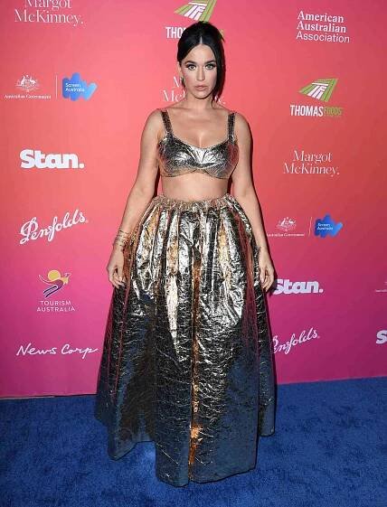 Katy Perry with her hair up while wearing a two-piece sparkly bralette top and skirt
