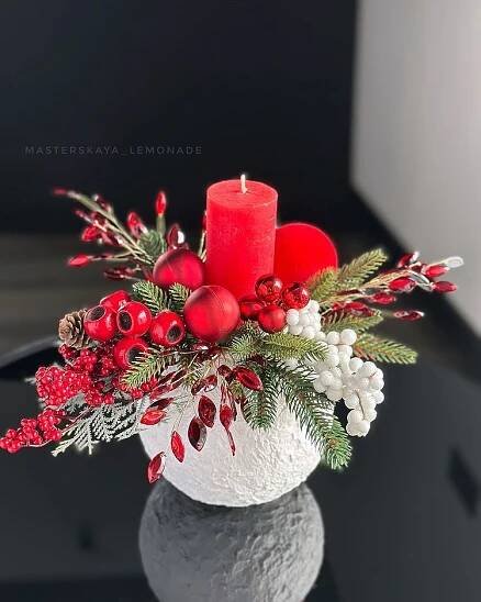 a white vase filled with red and green christmas decorations on top of a black table