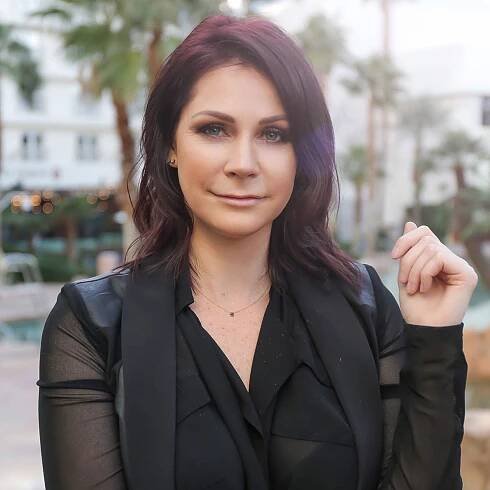 A woman in black shirt and jacket posing for the camera.