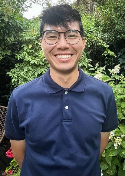 A smiling man wearing glasses and a blue shirt