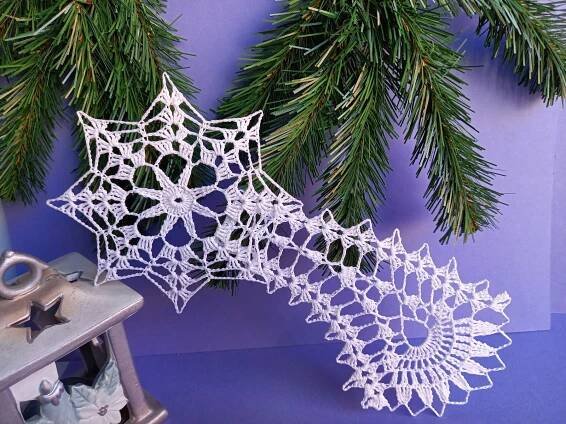 an ornament next to a christmas tree branch with snowflakes on it