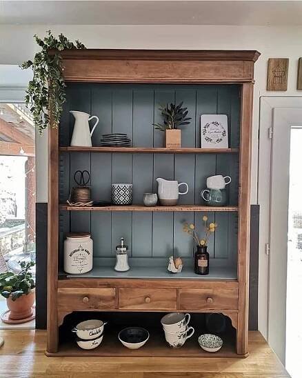 a wooden shelf filled with lots of dishes and cups on top of a hard wood floor