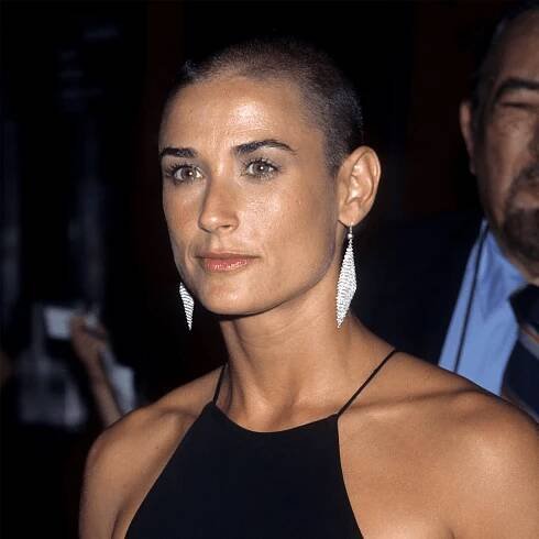 Demi Moore with a shaved head and long silver earrings