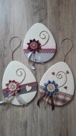 three handmade ornaments with ribbons and flowers on them sitting on a wooden floor next to scissors