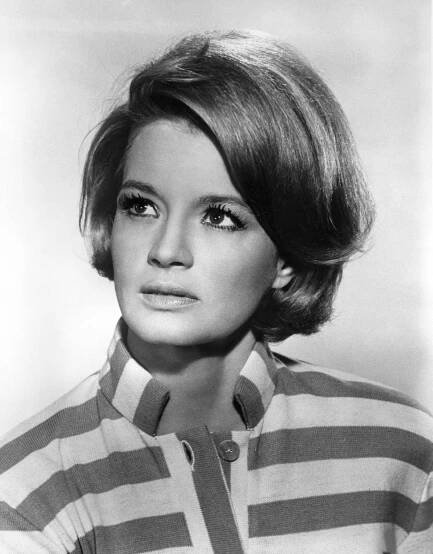 Person in a striped shirt with a thoughtful expression, looking upwards. Hair is styled in a neat bob