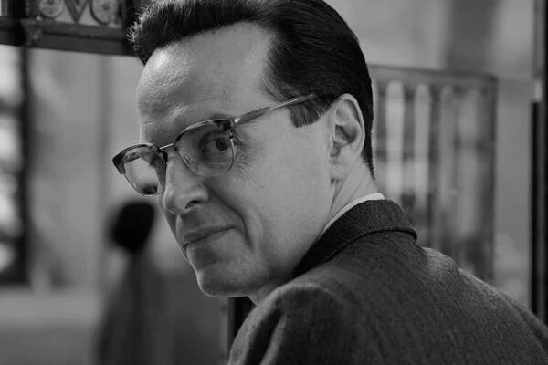 A close-up black-and-white still of the actor Andrew Scott, wearing glasses, looking over his left shoulder.