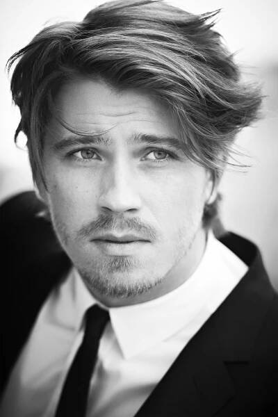 a black and white photo of a man in a suit looking at the camera with a serious look on his face