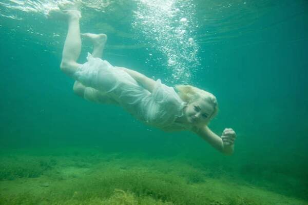 A floating woman. Underwater portrait. Girl in white dress swimming in the lake. Green marine plants and water A floating woman. Underwater portrait. Girl in white dress swimming in the lake. Green marine plants and water woman underwater dress stock pictures, royalty-free photos & images