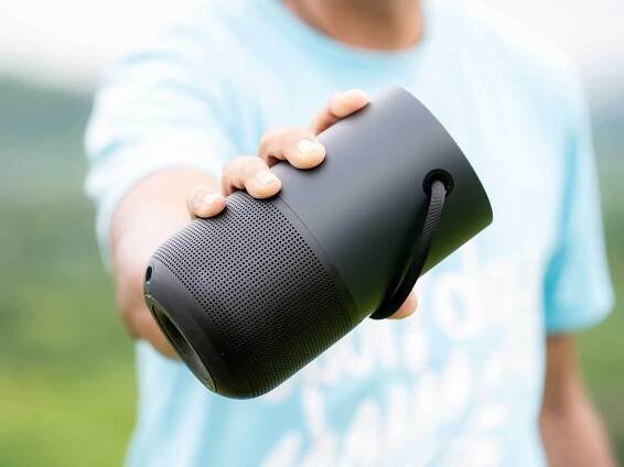 Bluetooth speaker being held up by a man wearing a blue t shirt