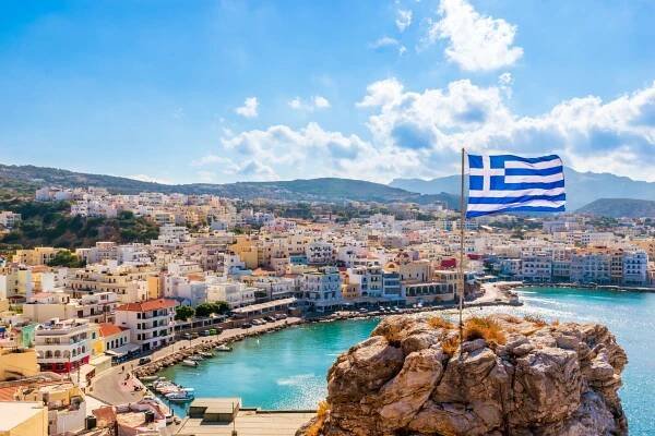 Pigadia or Karpathos town is the capital of the Greek island of Karpathos. It is located on a scenic bay with a harbor, long beach and next to a rocky hill with a Greek flag on top.