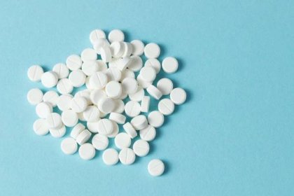 pile of white round pills on blue background