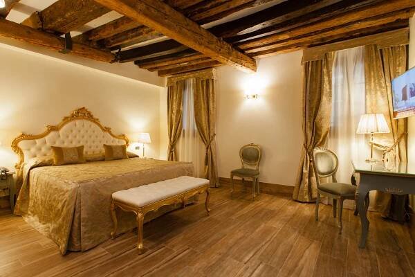 A guest room in golden tones at Al Ponte Mocenigo hotel in Venice